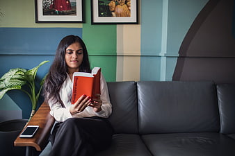 Woman Reading Book on Couch in Colorful Room