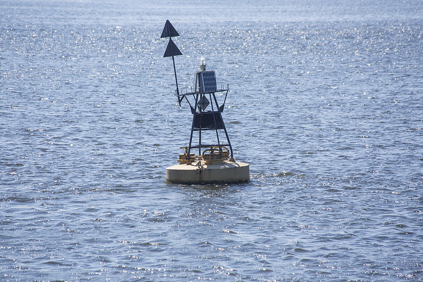 Navigation buoy floating on shimmering blue water