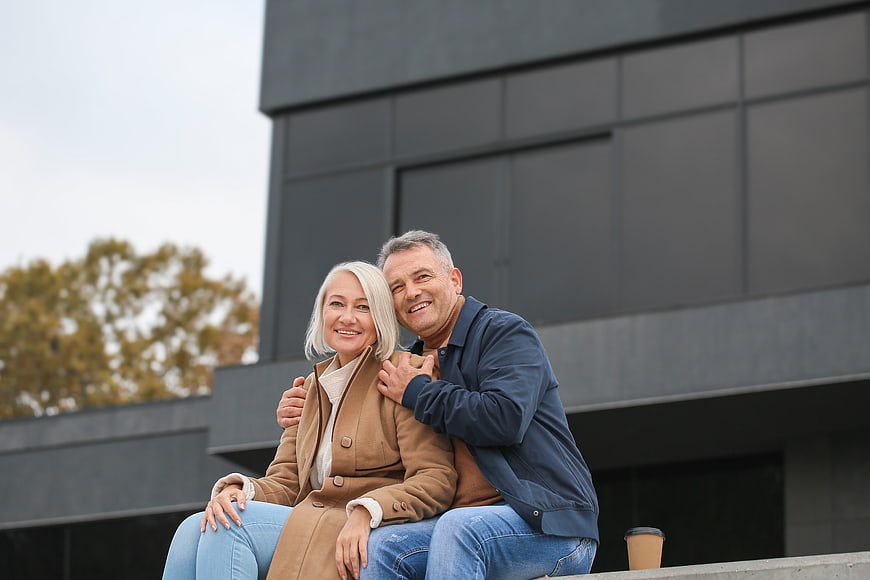 Happy Senior Couple Sitting Outside Modern Building