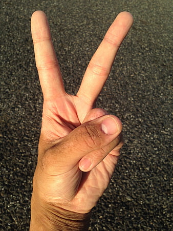 Hand making peace sign gesture on asphalt background