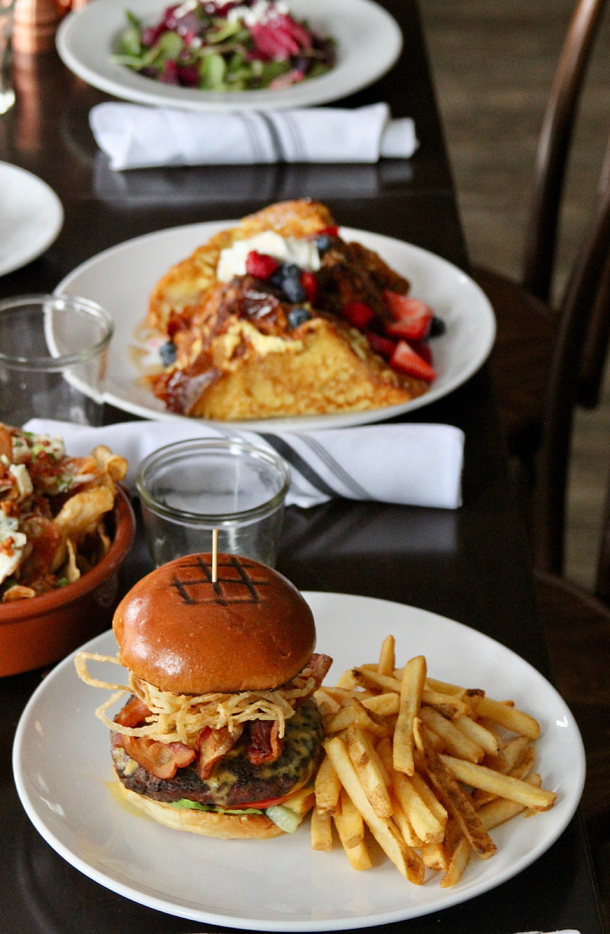 Delicious burger with fries and brunch spread on dark table
