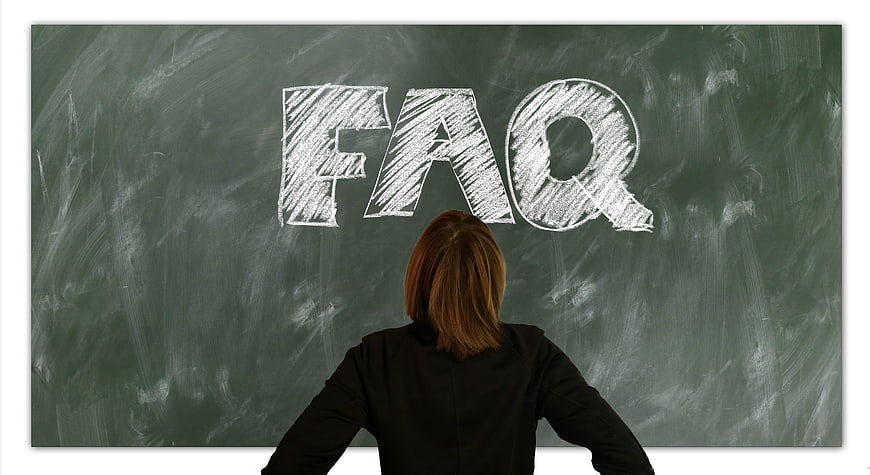 Woman standing in front of chalkboard with FAQ written