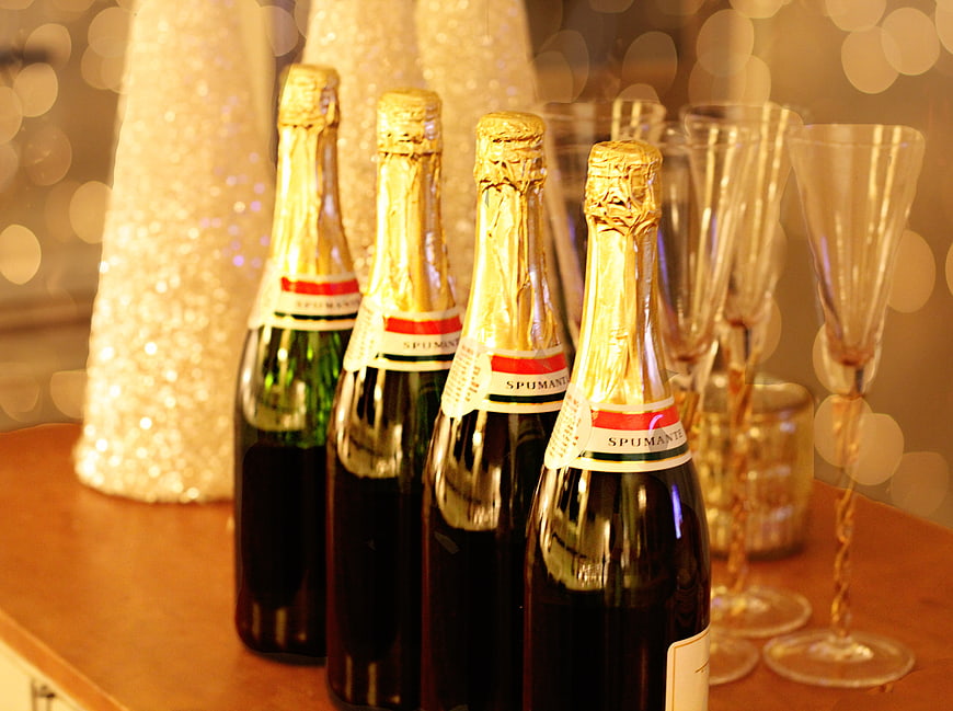 Four Spumante Bottles and Flutes on Wooden Table