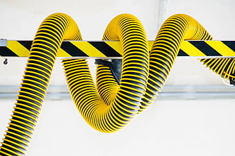 Yellow and black corrugated industrial hose on striped rail