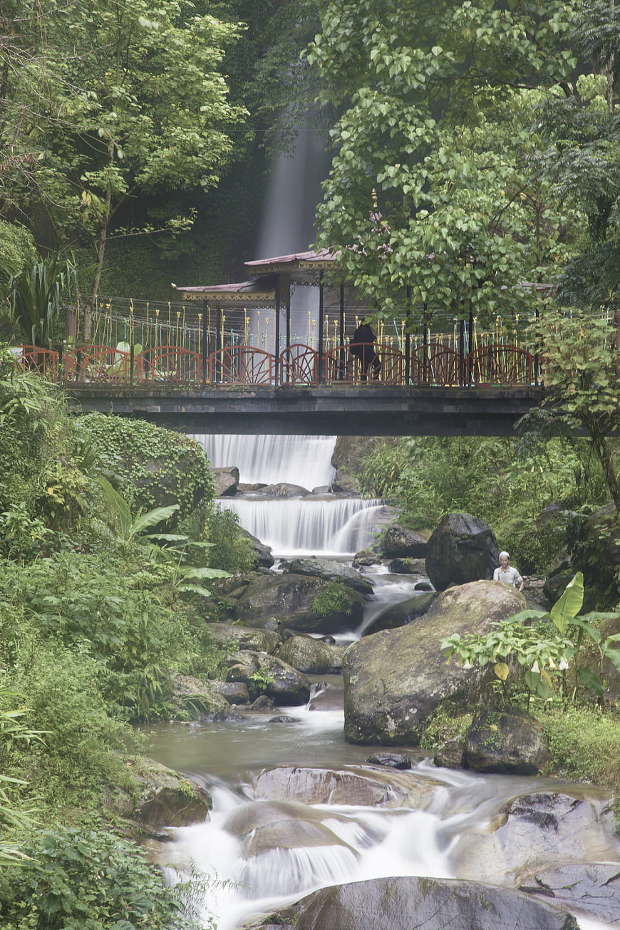 Scenic waterfall with bridge and lush green forest landscape