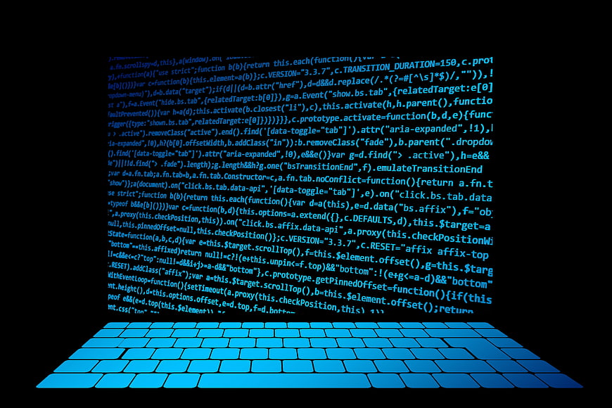 Glowing blue computer code floating above a backlit keyboard on black background
