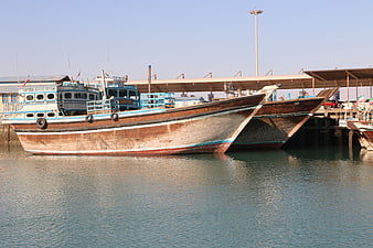Traditional wooden fishing boats docked at a sunny harbor
