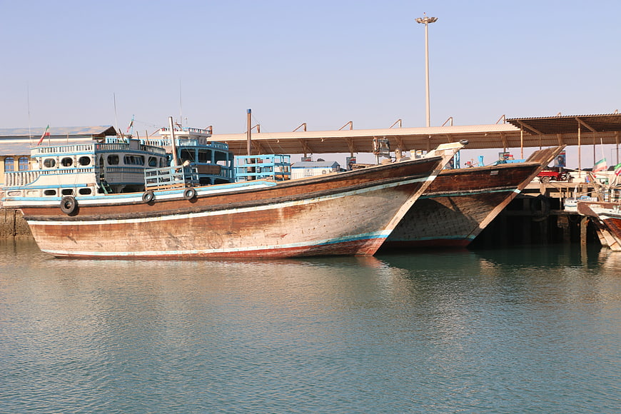 Traditional wooden fishing boats docked at a sunny harbor