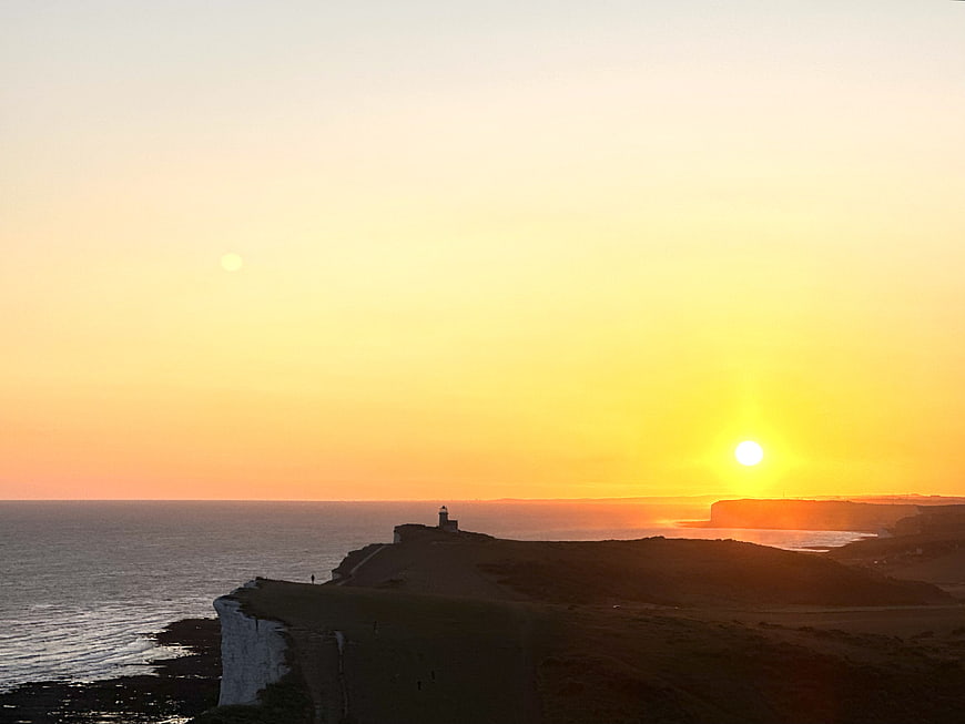 Sunset over white cliffs and lighthouse coastal landscape