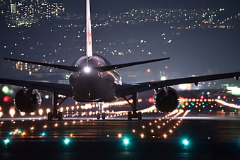 Airplane on Runway at Night with City Lights Background
