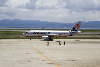 Jetstar airplane taxiing on airport tarmac with mountains