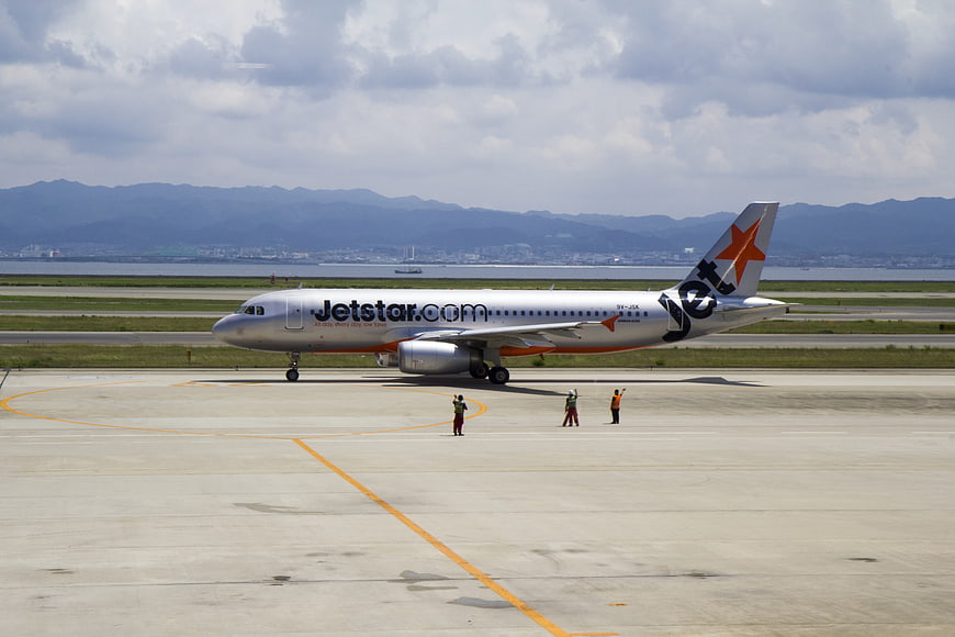 Jetstar airplane taxiing on airport tarmac with mountains