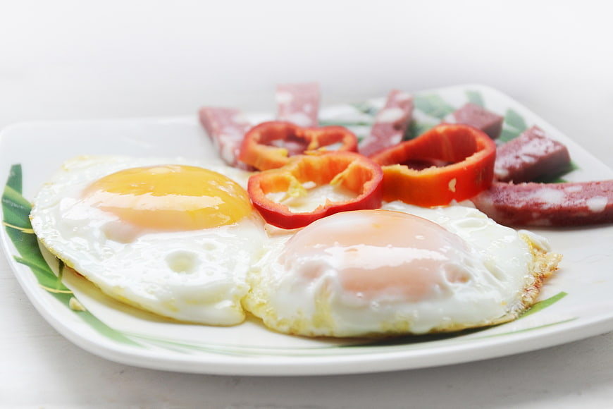 Fried Eggs with Sausage and Peppers on White Plate