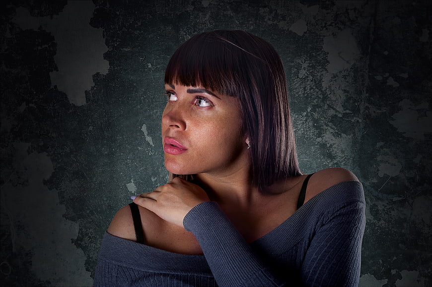 Portrait of Woman Looking Up Against Dark Textured Wall