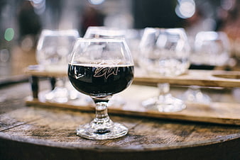 Dark beer in tasting glass on wooden barrel