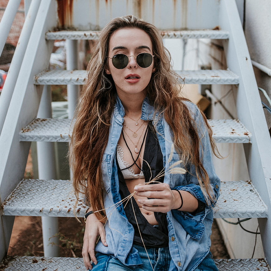Stylish Woman in Denim Jacket Sitting on Metal Stairs