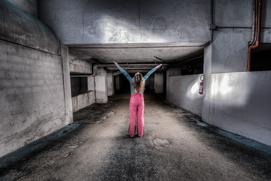 Woman in pink overalls standing in concrete tunnel