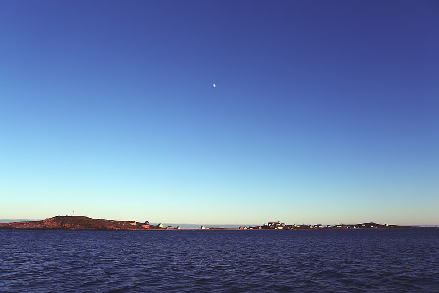 Coastal village landscape with crescent moon in blue sky