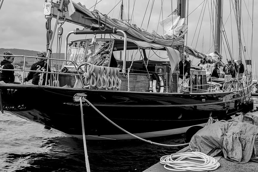 Black and white photo of a classic sailing yacht docked at a marina