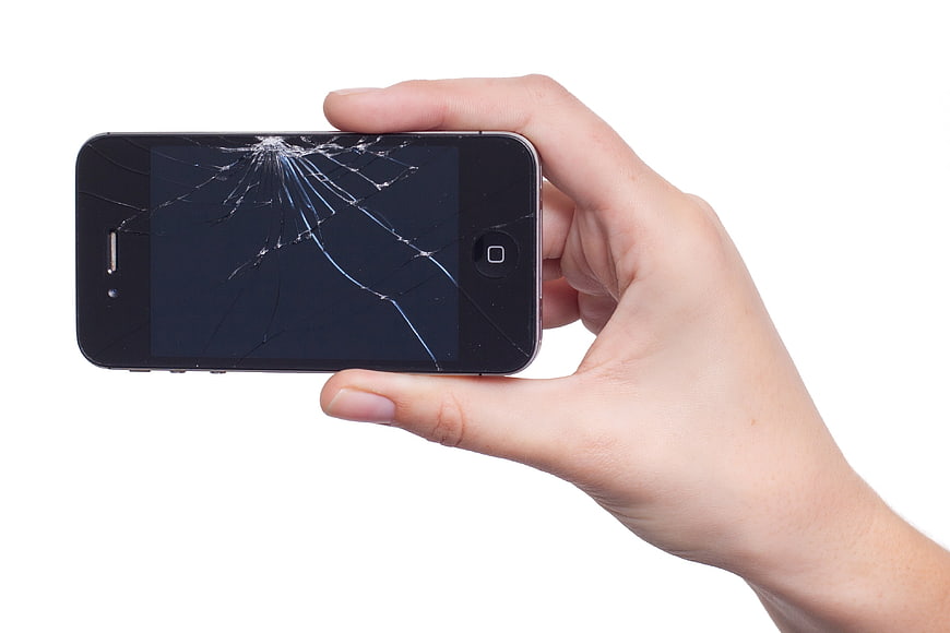Hand holding smartphone with cracked screen on white background