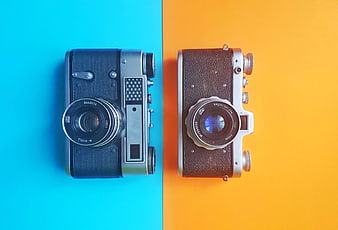 Two vintage film cameras on split blue and yellow background