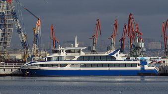Blue and white passenger ferry docked at industrial port