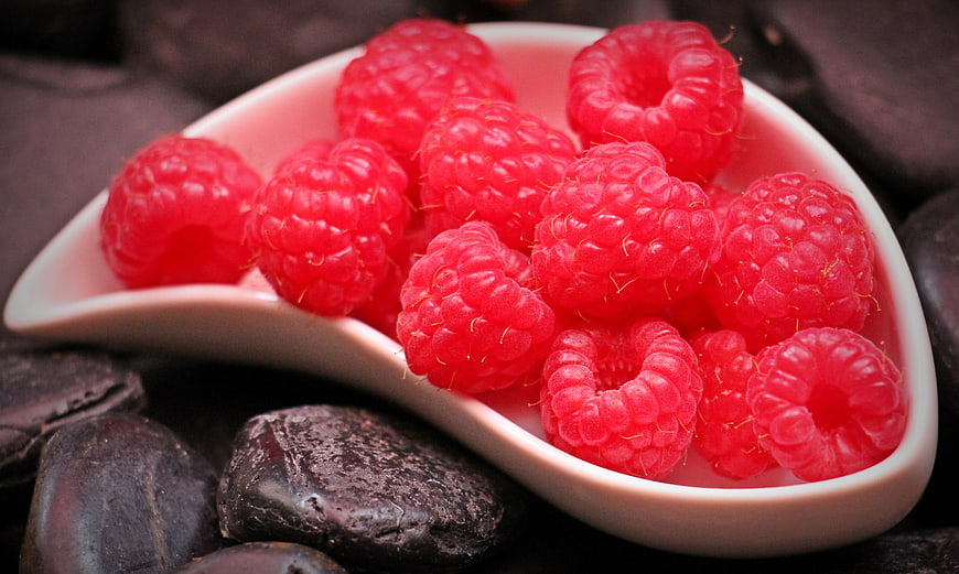 Fresh Red Raspberries in White Ceramic Spoon on Dark Stones