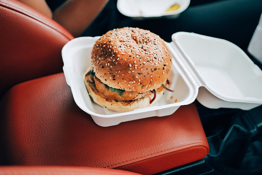 Delicious Burger in Takeout Container on Car Seat