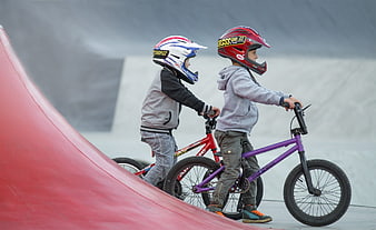 Two young children on BMX bikes at a skatepark