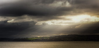 Dramatic sunbeams breaking through storm clouds over a lake