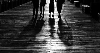Silhouettes of four people walking on a wooden pier