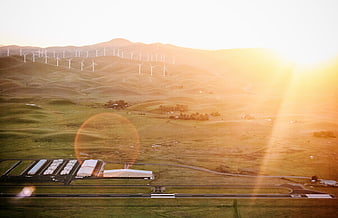 Aerial view of wind turbines on hills near airport runway at sunset