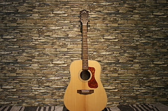 Acoustic Guitar Leaning Against Textured Stone Wall