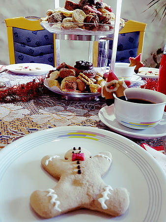 Christmas gingerbread man cookie on white plate with holiday treats