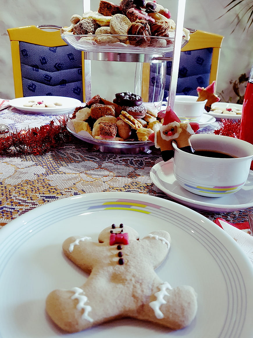Christmas gingerbread man cookie on white plate with holiday treats