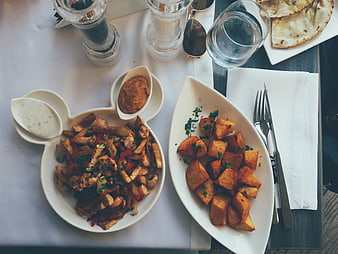 Overhead view of chicken stir fry and roasted potatoes on white plates