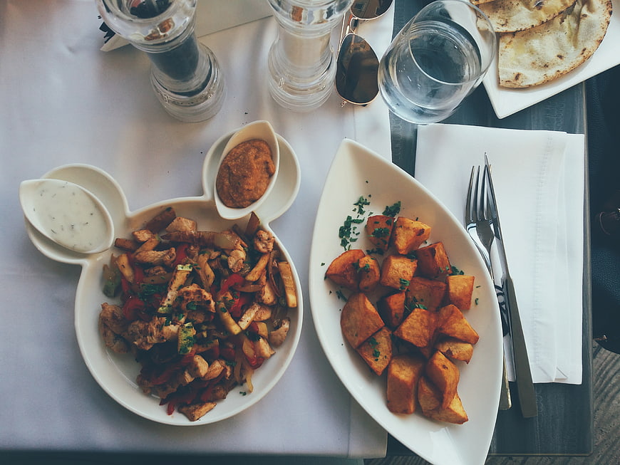 Overhead view of chicken stir fry and roasted potatoes on white plates