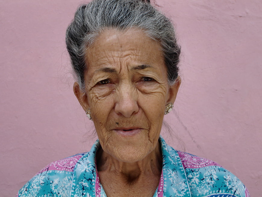 Portrait of elderly woman with gray hair against pink wall