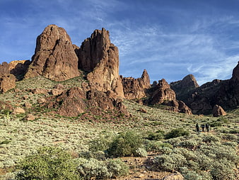 Hikers trekking through desert landscape with red rock formations