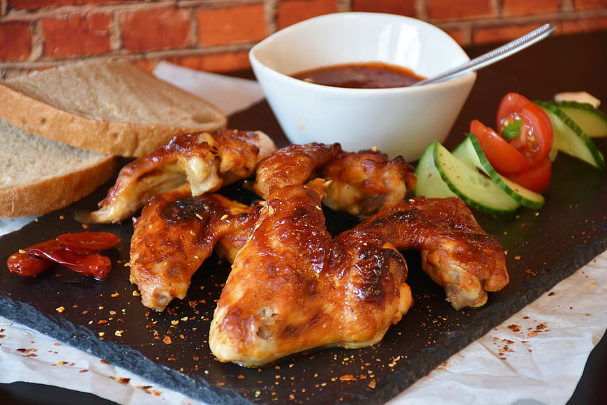 Spicy grilled chicken wings with dipping sauce on slate