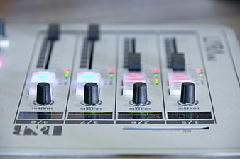 Close-up of DJ mixer control panel with knobs and sliders