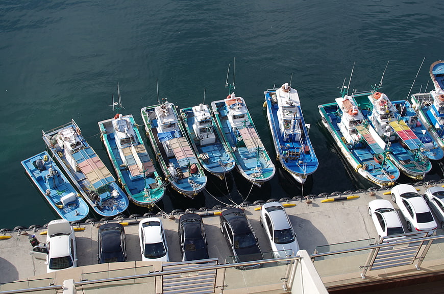 Aerial view of fishing boats and cars docked at a harbor