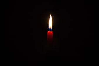Single red candle burning in the dark
