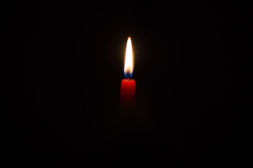 Single red candle burning in the dark