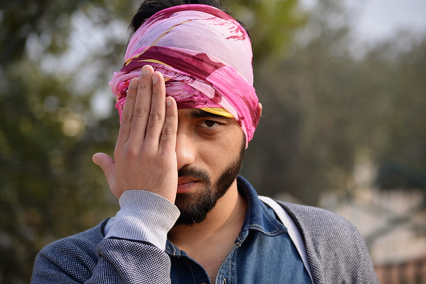 Portrait of man with pink headscarf covering one eye