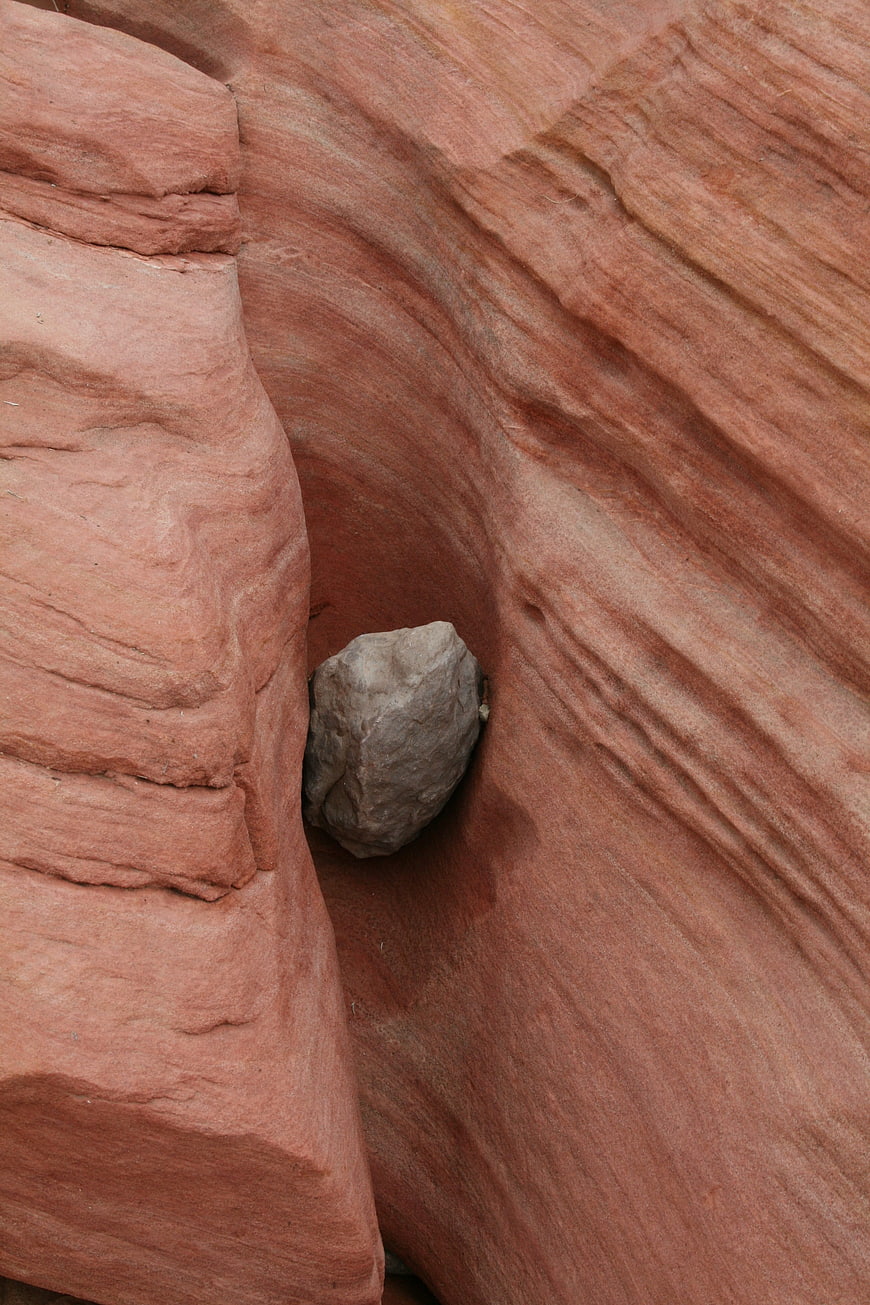 Close-up of gray boulder wedged in red sandstone canyon