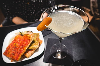 Cocktail with dried apricot garnish and savory appetizer