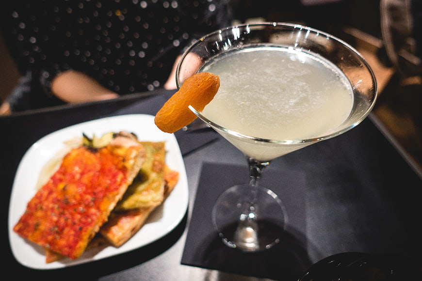 Cocktail with dried apricot garnish and savory appetizer