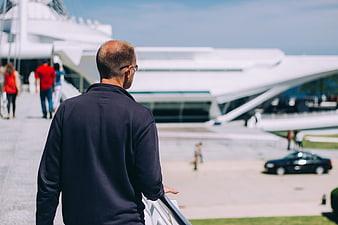 Man in Navy Sweater Looking at Modern White Architecture