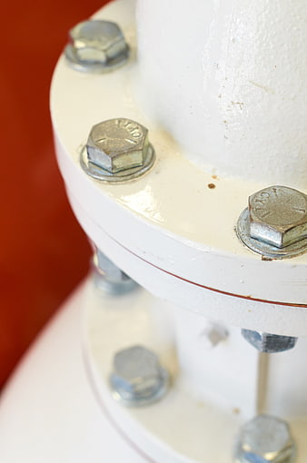 Close-up of white industrial pipe flange with metal bolts
